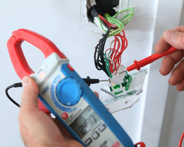 Clamp meter testing a circuit at the ceiling
