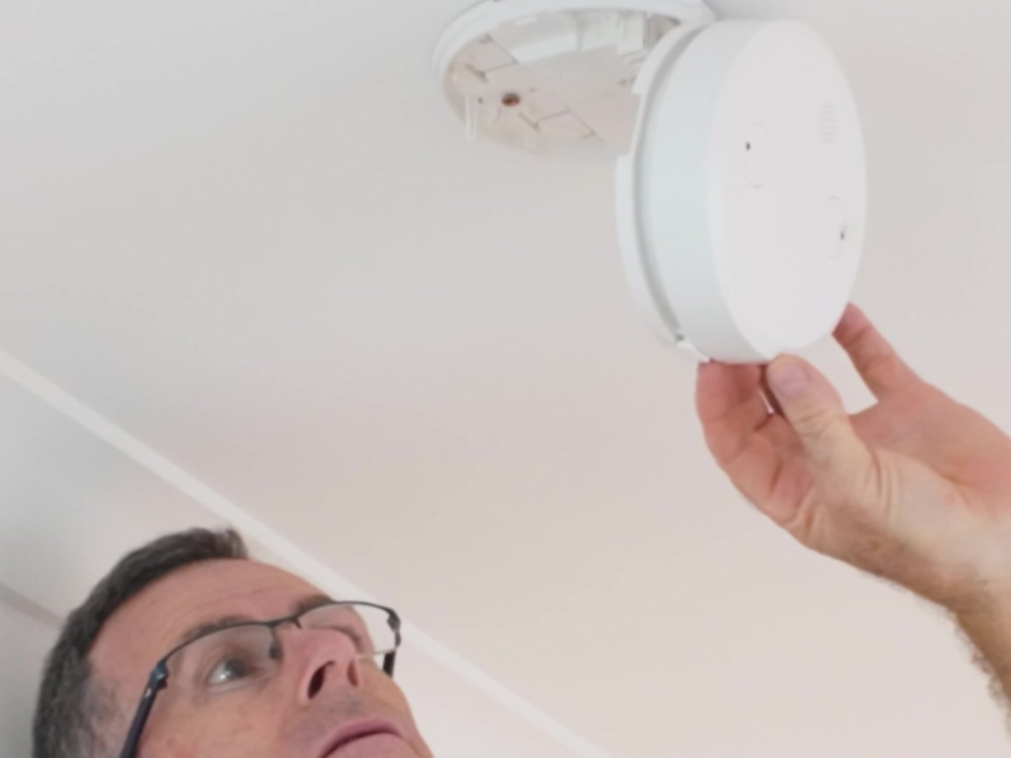 Darren fitting an interconnected photoelectric smoke alarm to a ceiling